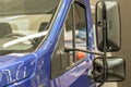 Door, windshield and hood with reflections on it. Front part blue cargo vehicle truck body with rear view mirrors close-up