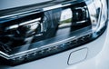 Front part of brand new modern white car. Parked at showroom. Reflection in the headlights Royalty Free Stock Photo