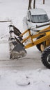 The front part of a bulldozer tractor engaged in clearing snow in a parking lot for cars Royalty Free Stock Photo