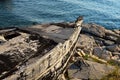 Front part of old decaying fishing boat placed on damaged rocky molo, used as storage for fishnets and fishing equipment.