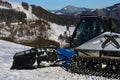 Front part of snow groomer Prinoth LeitWolf with icicles on bottom of the cabin and chassis, parked on top of ski slope