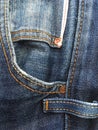 Front pocket with rivets and stitching on blue retro jeans.