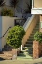 Front porch entranceway with brown brick facade and beige stucco cement with shrubs and sidewalk on house or home