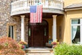 Front porch of home with American flag hanging from balcony Royalty Free Stock Photo