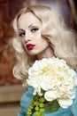 Front portrait of a beautiful young blonde woman with curly hair and makeup, looking at camera, dressed in a blue dress. Royalty Free Stock Photo