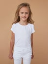 Front portrait of pretty little timid girl with wavy hair, dressed in white clothes. Vertical view