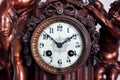 A front portrait of the retro clock face of an old vintage clock made of wood and metal with beautiful clock hands and numbers for