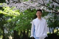 smile handsome Asian young man under white sakura blossom tree Royalty Free Stock Photo