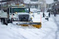 Front right view of city services snowplow truck clearing roadways of snow after winter storm covered streets in urban area Royalty Free Stock Photo