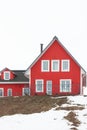 A front shot of a red wooden house with several white windows with a tube coming through a dark roof. Clear white sky is on top of Royalty Free Stock Photo