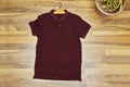 Front side of male garnet cotton t-shirt on wood floor with cactus pot. Royalty Free Stock Photo