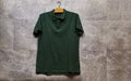 Front side of male green cotton t-shirt hanging on gray grunge marble wall . Royalty Free Stock Photo