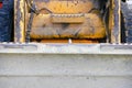 Front side of an old little scratched orange bulldozer. building background