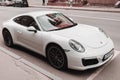 Front side view of car Porsche 911 in city area. White luxury Porsche 991 parked on the street