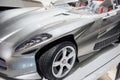 Front, side view of left headlight, mirror, chrome wheel disc of modern roofless grey sport coupe car