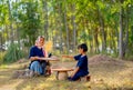 Front and side view of senior Asian woman with traditional clothes winnow rice using basketry and little girl stay beside and also