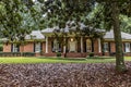 A front side view of an updated spacious red brick ranch traditional house home with off white columns and brick front steps with Royalty Free Stock Photo