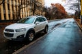 Front side view of white crossover Chevrolet Captiva parked along wet street. Car Chevrolet in autumn landscape Royalty Free Stock Photo