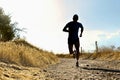 Front silhouette young sport man running cross country workout at summer sunset