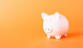 Front small white fat piggy bank, studio shot isolated on orange