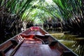 Front of Thai old wooden boat floating on canal river water and moving through wild woods Nipa palm green tree tunnel in Surat Royalty Free Stock Photo