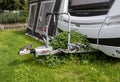 Front of touring caravan showing hitch which is overgrown with plants and awning