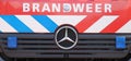 Front of truck of the fire brigade in The Netherlands called Brandweer in red car with blue and white striping.