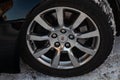 Front turned alloy chrome wheel view of Cadillac CTS in black color after cleaning before sale in a winter day and snow background