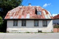 Front view of abandoned small urban family house on cracked stone and concrete foundation with rusted metal roof tiles