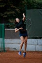 front view of active bouncing female tennis player with tennis racket in her hand behind her back Royalty Free Stock Photo