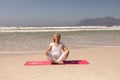 Front view of senior woman meditating at beach on a sunny day Royalty Free Stock Photo