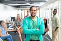 Businessman with arms crossed looking at camera while diverse colleagues standing in background Royalty Free Stock Photo