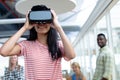 Businesswoman using virtual realty headset while diverse colleagues standing in background Royalty Free Stock Photo