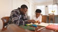 African American father helping his son with homework at table Royalty Free Stock Photo