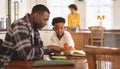 African American father helping his son with homework at table Royalty Free Stock Photo