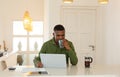 Man drinking coffee while working on laptop at dining table in kitchen at comfortable home Royalty Free Stock Photo