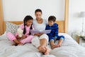 Mother and children reading a story book on bed in bedroom Royalty Free Stock Photo