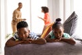 Upset children sitting on a sofa while their parents arguing in the background Royalty Free Stock Photo