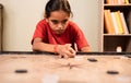 Front view of alone Young girl kid practicing or playing Carrom board at home - Concept of autism and introvert. Royalty Free Stock Photo