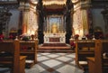 Front view of an altar in a large catholic church with wooden benches Royalty Free Stock Photo