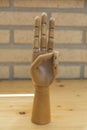 Articulated wooden hand with three raised fingers Royalty Free Stock Photo