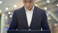 Front view of asian male businessman in suit working with laptop on his knees Royalty Free Stock Photo