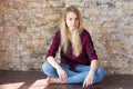 Front view of attractive white girl sitting on wooden floor