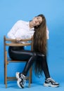 Attractive woman with languid gaze, showing long wavy fair hair, while posing at camera in studio.