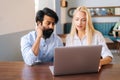 Front view of attractive young female manager showing computer presentation via laptop to male client sitting at table Royalty Free Stock Photo