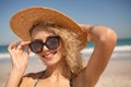 Woman in hat and sunglasses looking at camera on the beach Royalty Free Stock Photo
