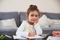 Front view of a beautiful girl holding a pen and looking at camera. Concept of study at home. Portrait of a preschool girl