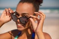 Beautiful woman looking over sunglasses on beach in the sunshine Royalty Free Stock Photo