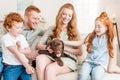 Front view of beautiful redhead family playing with puppy at home Royalty Free Stock Photo