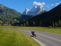 Front view of beautiful Swiss moutains on a sunny day with couple riding on foreground on motorcycle on high speed with blur